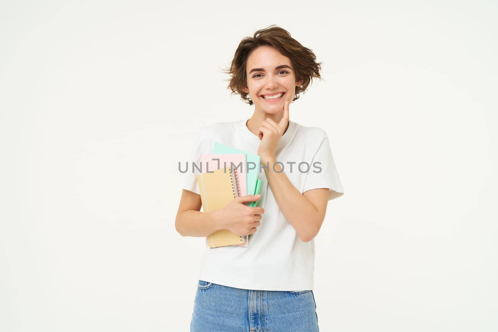 Image of stylish, modern girl student, holding workbook, documents. Woman teacher with papers standing over white background.