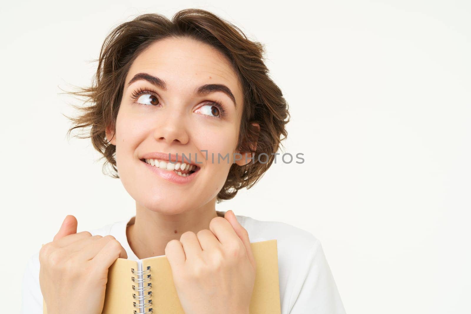 Portrait of happy woman with planner, holding notebook, reading notes and smiling, standing over white background by Benzoix