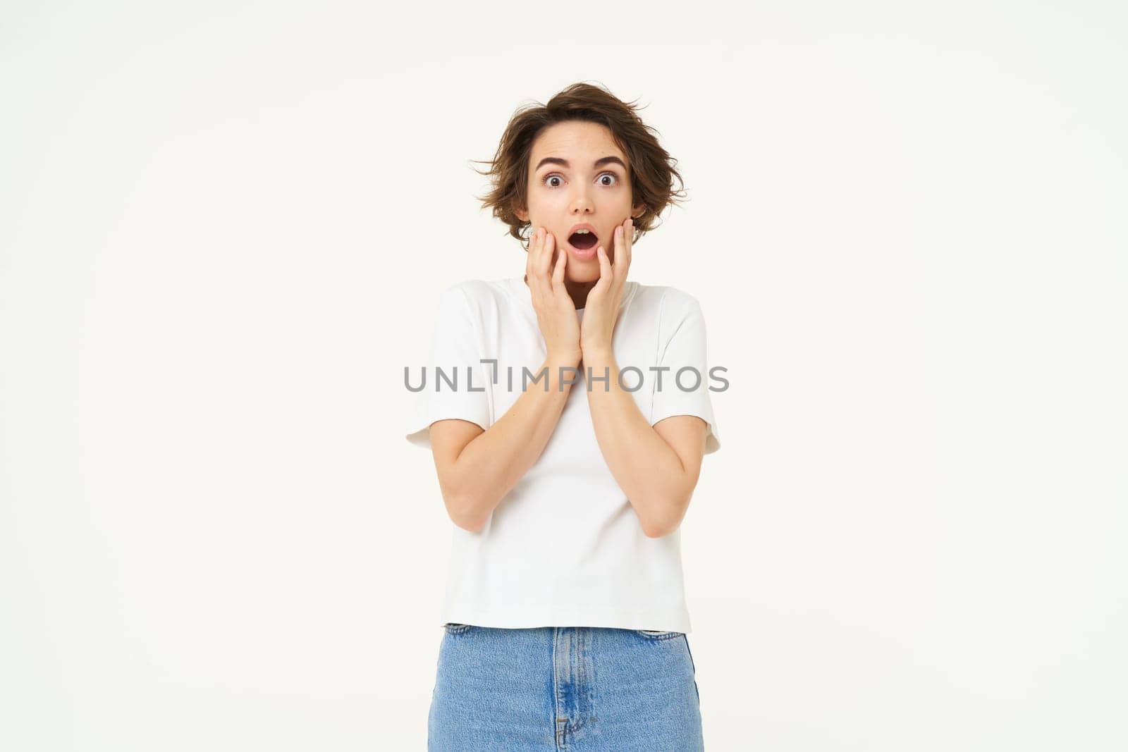 Image of woman with shocked face, looks frightened in panic, stands against white studio background by Benzoix