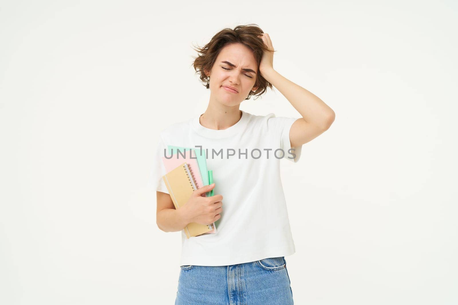 Troubled woman touches her head, looks upset, holds documents, standing frustrated against white studio background. Copy space