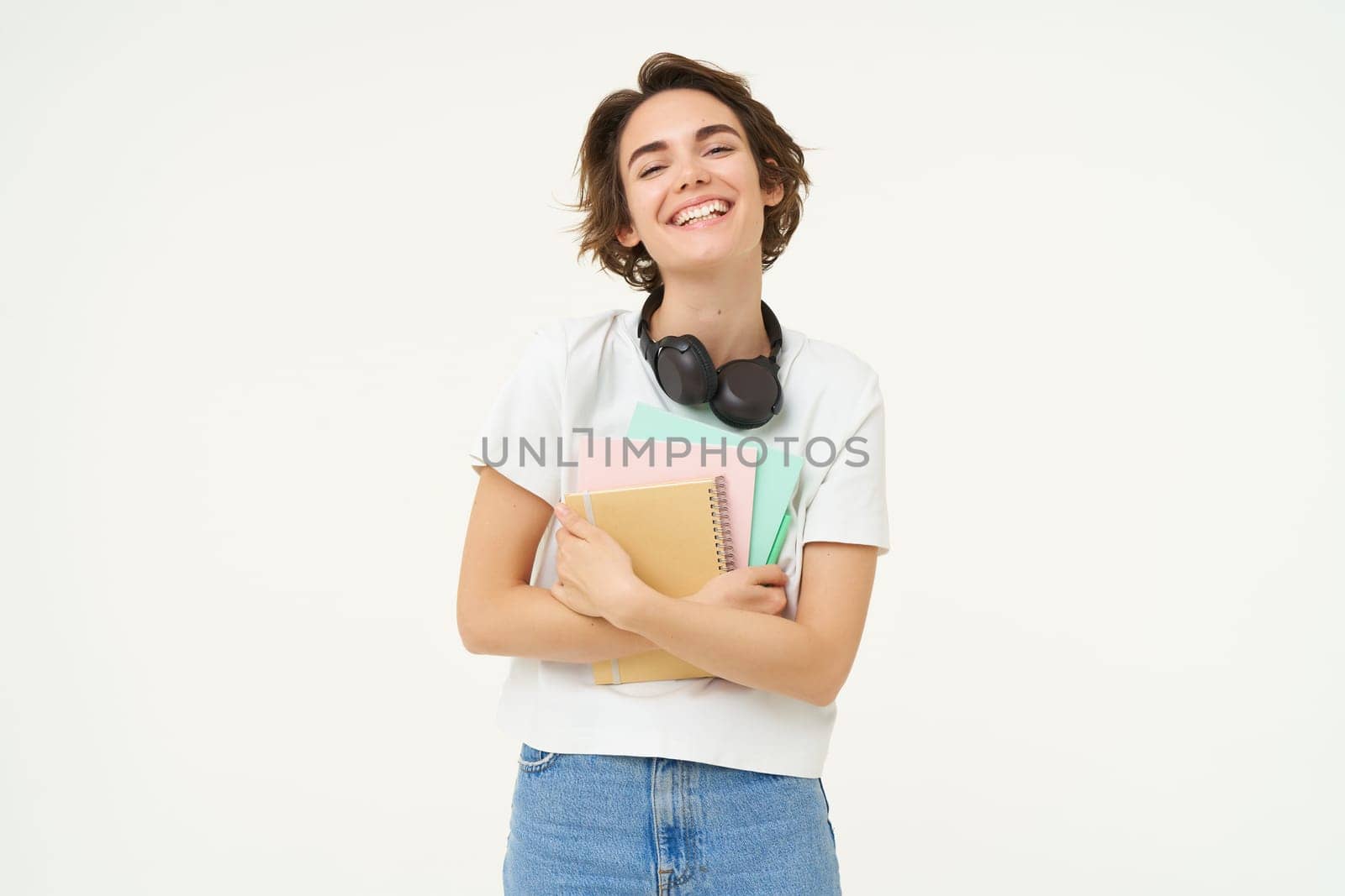 Image of carefree, smiling woman with notebooks, laughing and looking happy, posing over white background.