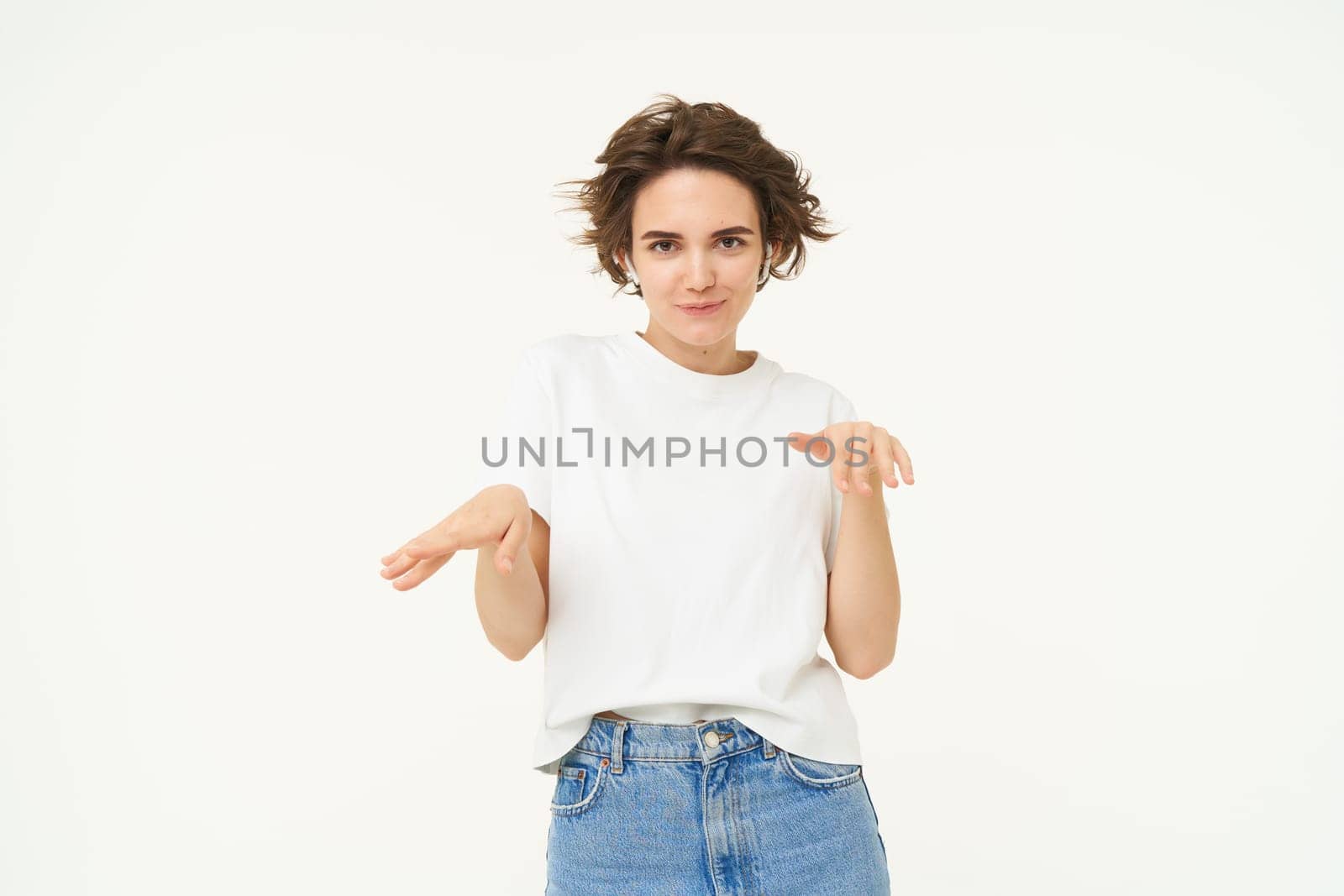Portrait of happy young woman dancing, having fun, enjoying the music, posing over white studio background. Copy space