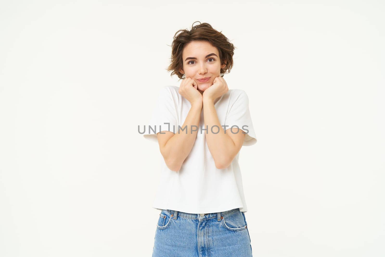 Portrait of woman making cute pose, gazing with admiration and love, posing over white background. People and lifestyle concept