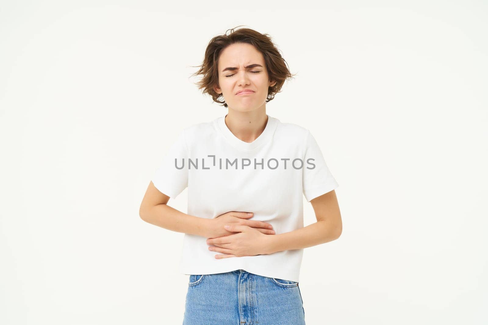 Image of woman with stomach ache, touching her belly, grimacing from pain or discomfort, has painful menstrual cramps, isolated over white background.