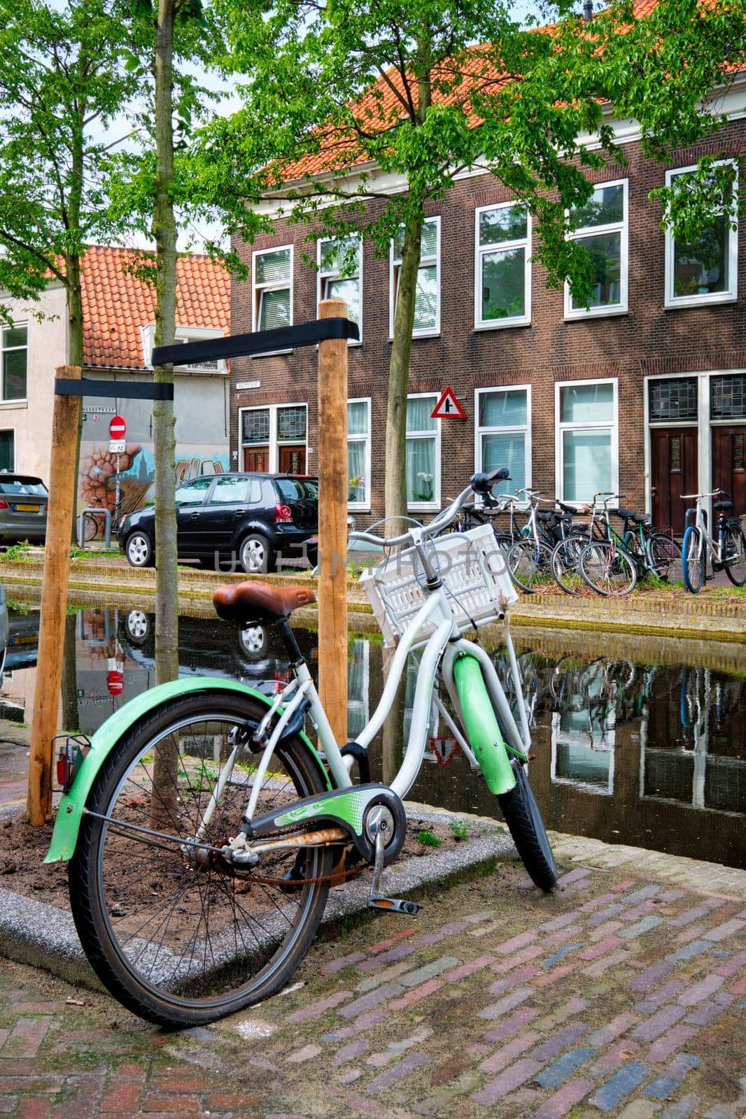 Bicycle parked near the canal in Delft street with old houses. Delft, Netherlands by dimol