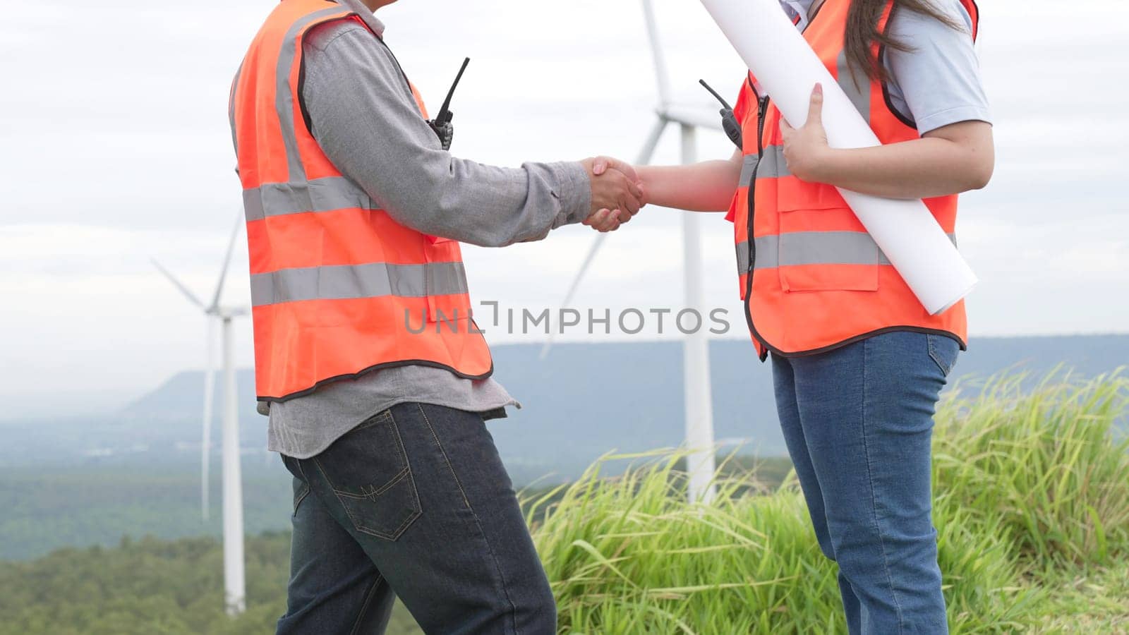 Male and female engineers working on a wind farm atop a hill or mountain in the rural. Progressive ideal for the future production of renewable, sustainable energy.