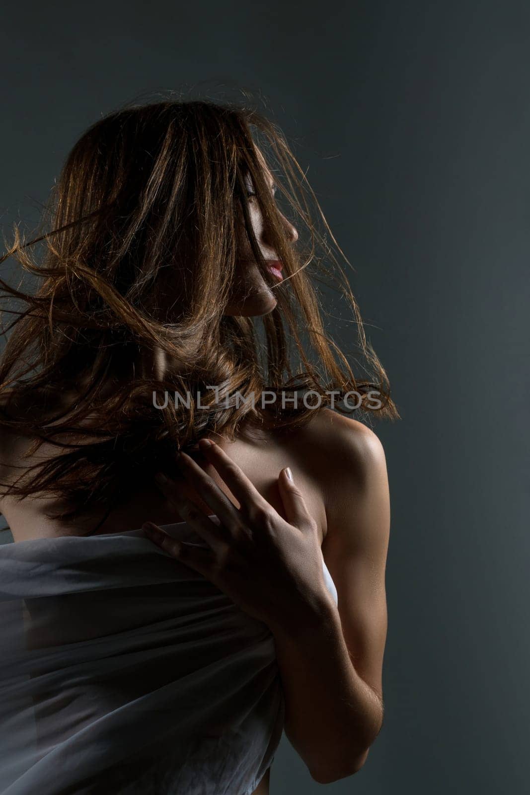 Girl in the nude wrapped in cloth portrait against gray background