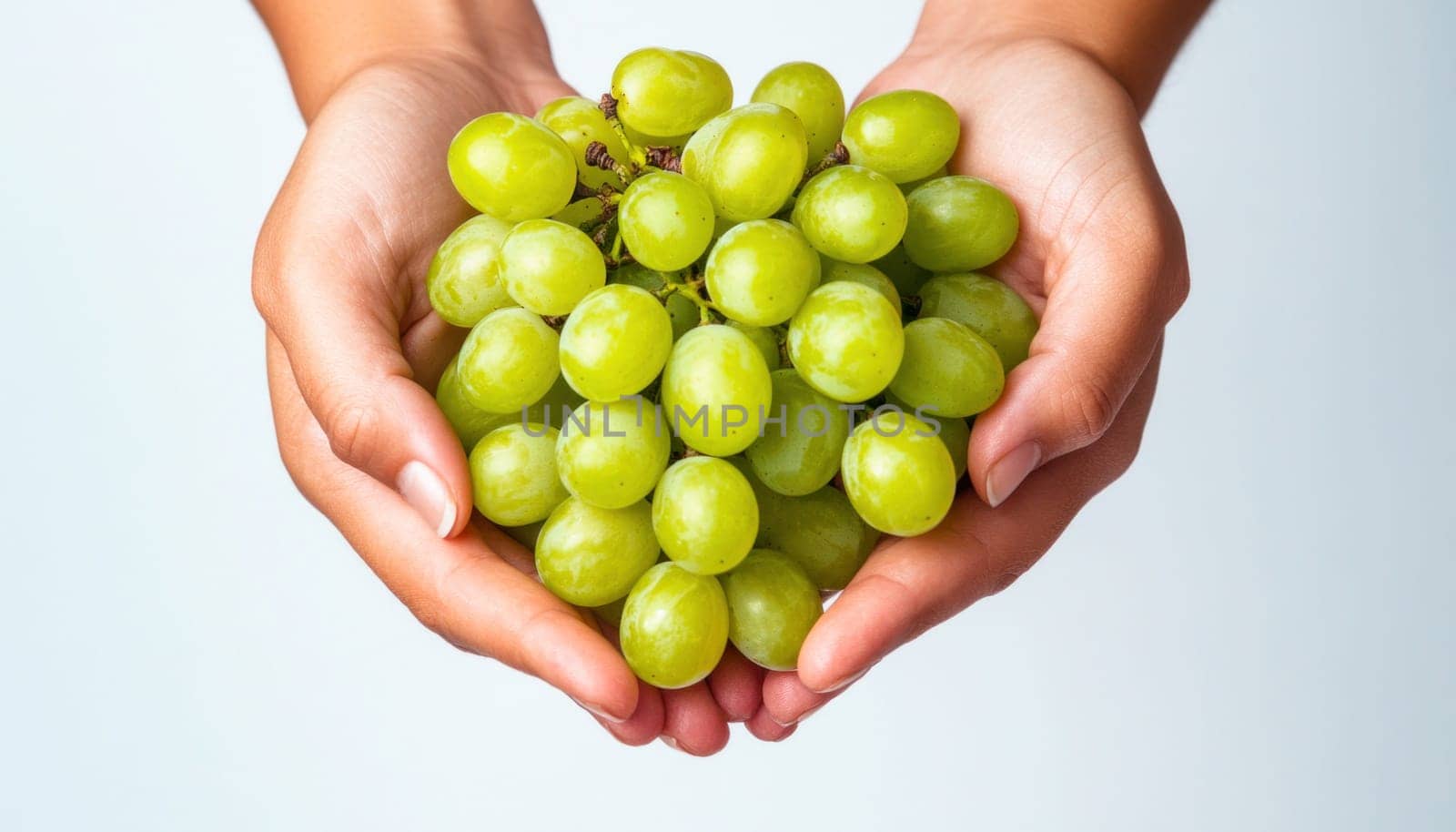 Woman holding bunch of fresh green grapes on white background