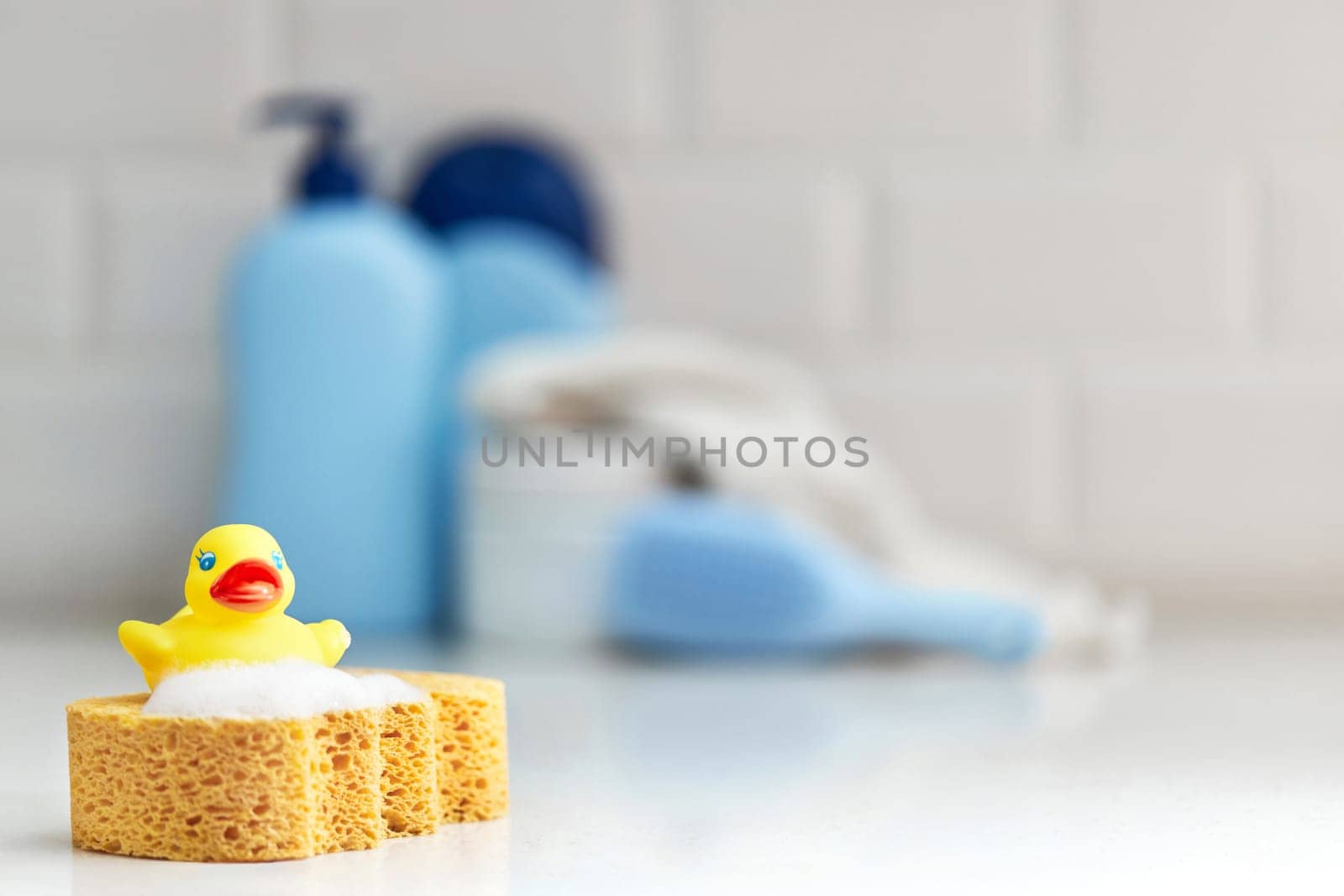 Yellow rubber duck, soap, bath foam on bath background, children bath accessories