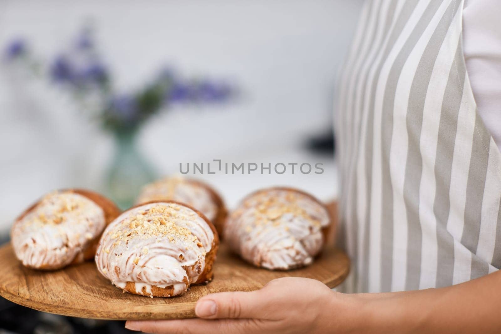 female baker holding wooden tray with freshly baked crispy golden croissants