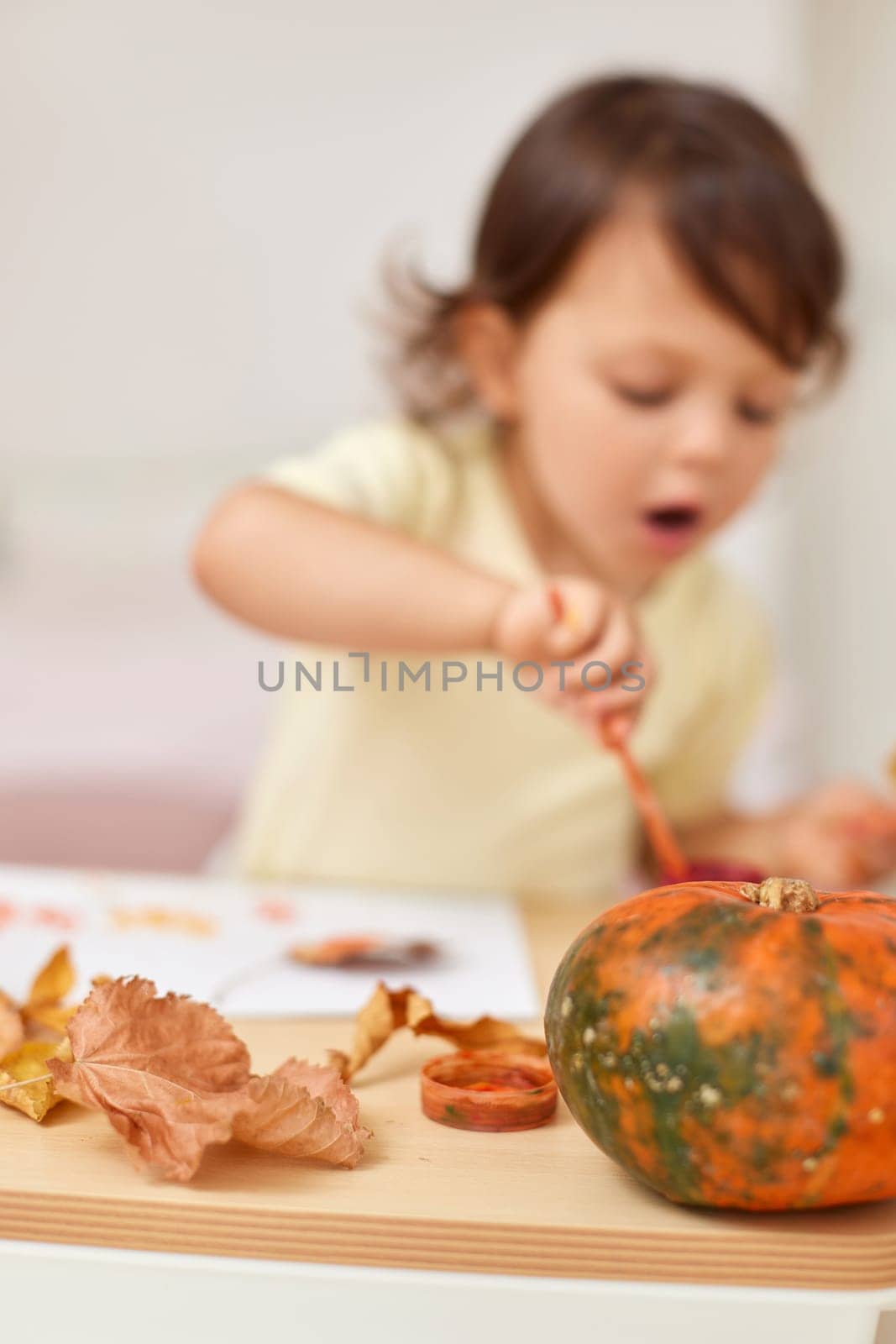 happy little child girl painting autumn leaves. baby girl drawing leaves in yellow and orange paint