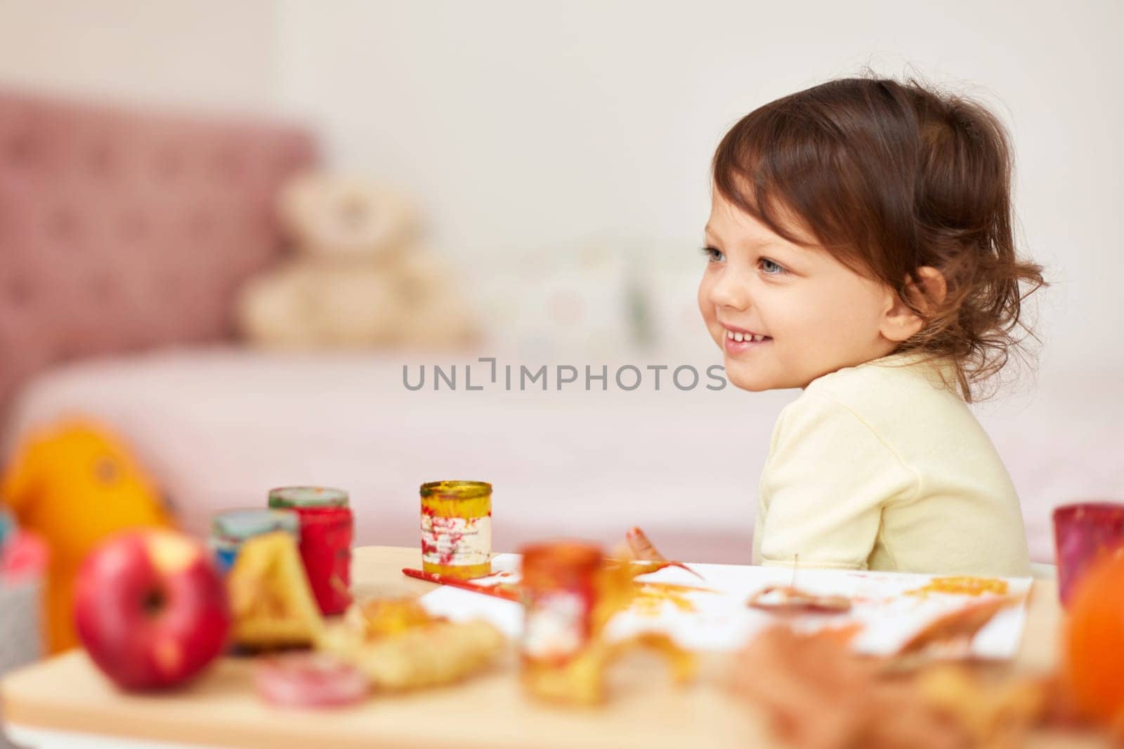 happy little child girl painting autumn leaves. baby girl drawing leaves in yellow paint