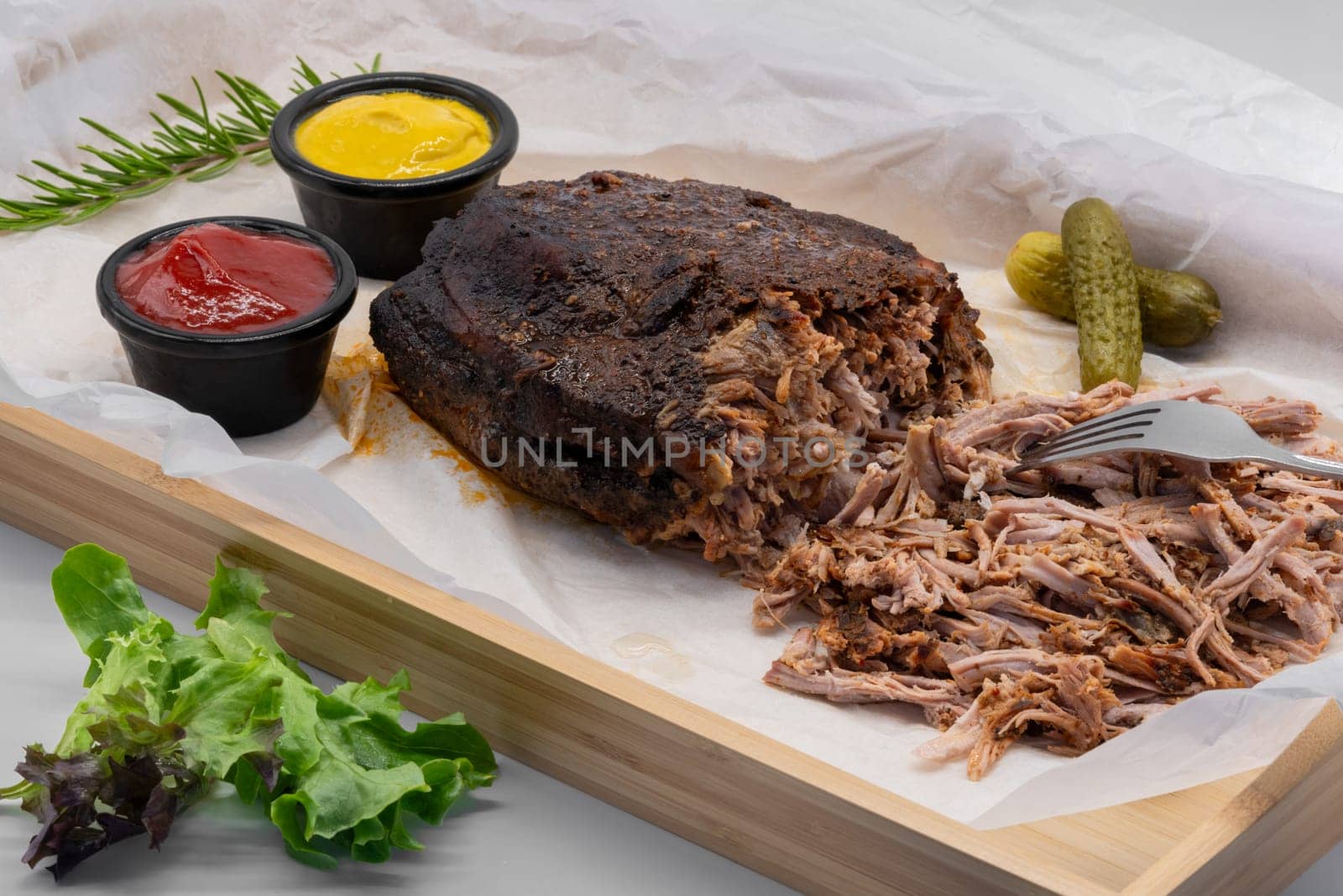 Tender, delectably pulled beef served generously with various flavorful sauces and pickles on a rustic wooden platter