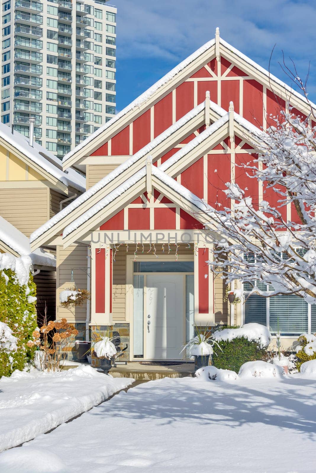 A perfect neighbourhood. Modern high-rise and private residential house in snow on winter season in British Columbia, Canada.