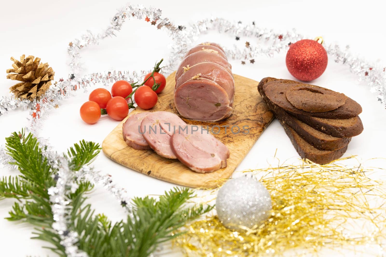 Baked Turkey roll with herbs, tomatoes and brown bread on a Christmas wooden background.