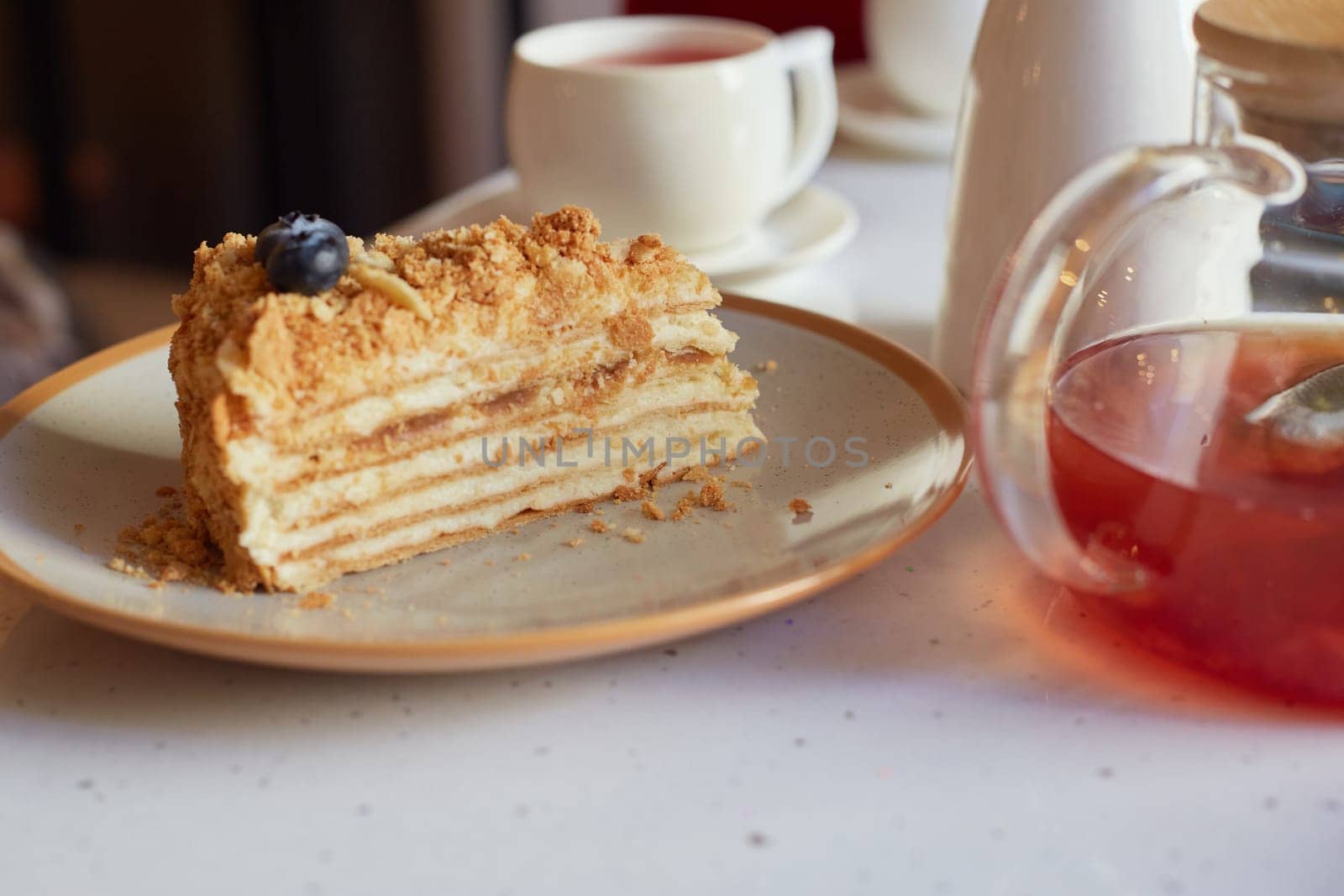 A piece of delicious fresh cheesecake on the table with a transparent teapot in the cafe. Delicious pastries, with a cup of hot tea. It's tea time. A sweet dish