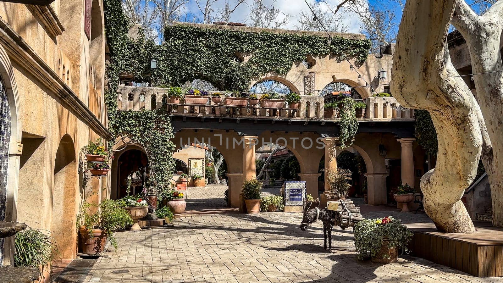Sedona, Arizona, USA - 03.20.2024: A beautiful courtyard in Tlaquepaque Arts and Shopping Village in Sedona. The courtyard features Spanish colonial architecture, with arches and stucco walls.