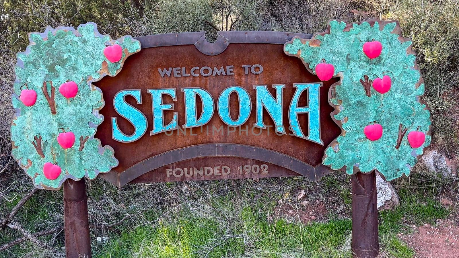 A whimsical welcome sign for the city of Sedona, Arizona. A still shot with the sign in the foreground and desert flora in the background. Founded in 1902, Sedona is a popular travel destination - USA