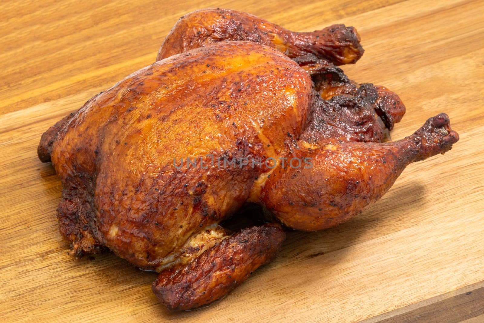 A beautifully roasted whole chicken, perfectly cooked, elegantly resting on a wooden cutting board surface