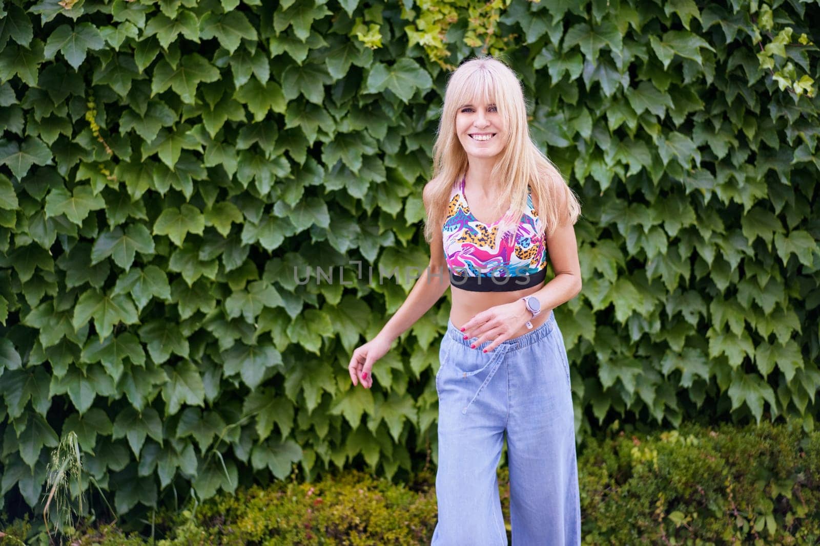 Happy female caucasian dancer smiling at camera while dancing next to an urban garden
