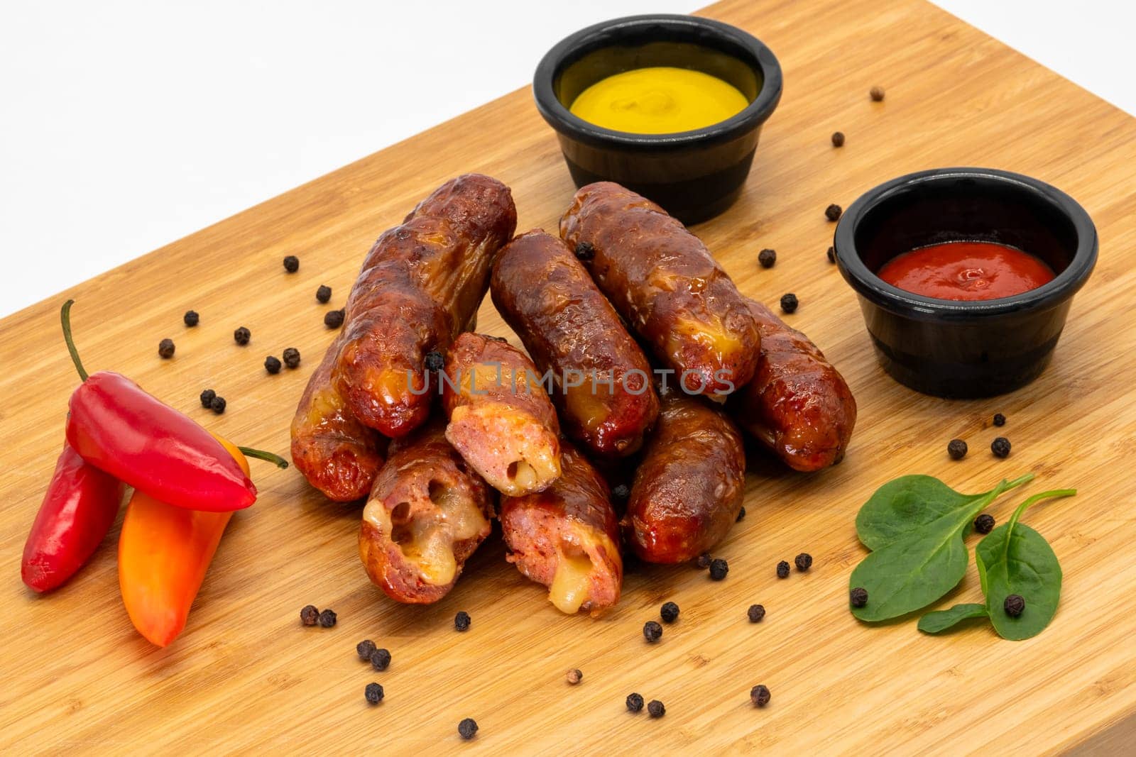Delicious, savoury grilled sausages are beautifully served with mustard, ketchup, and fresh peppers on a wooden board