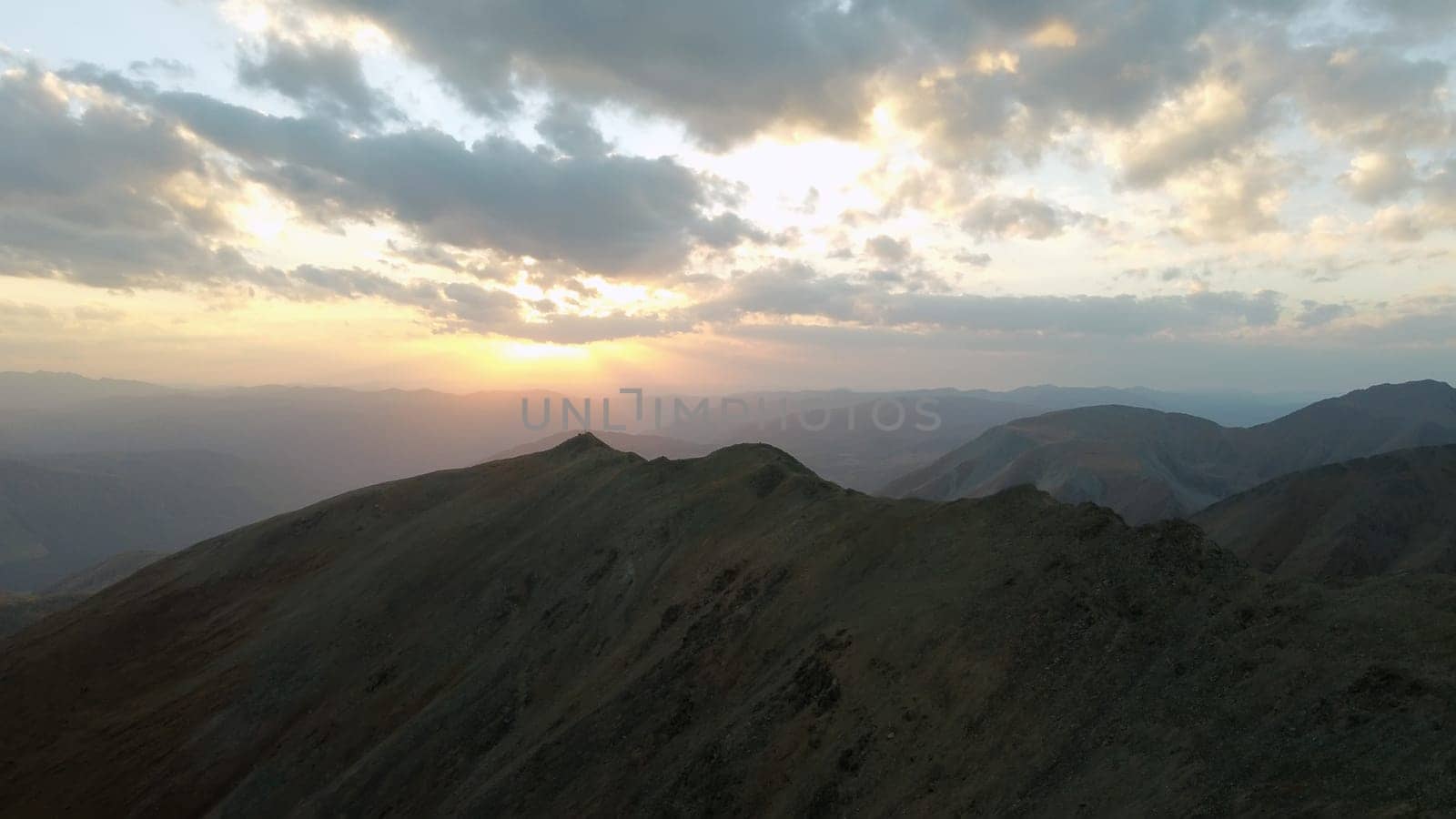 a mountain breathtaking river flows through the tranquil plain under the large clouds somewhere in the mountains, aerial panoramic view with no people