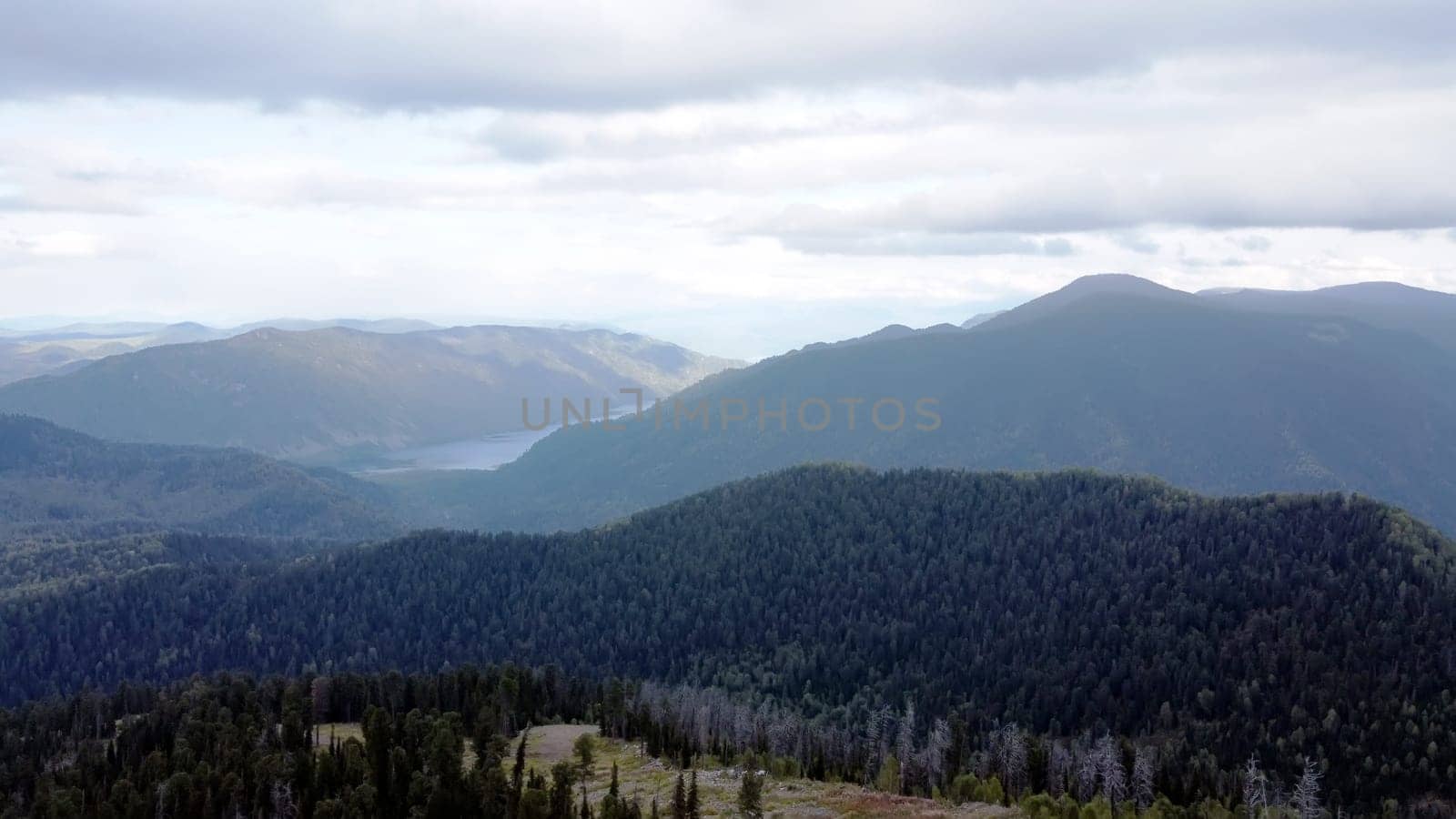 a mountain breathtaking river flows through the tranquil plain under the large clouds somewhere in the mountains, aerial panoramic view with no people