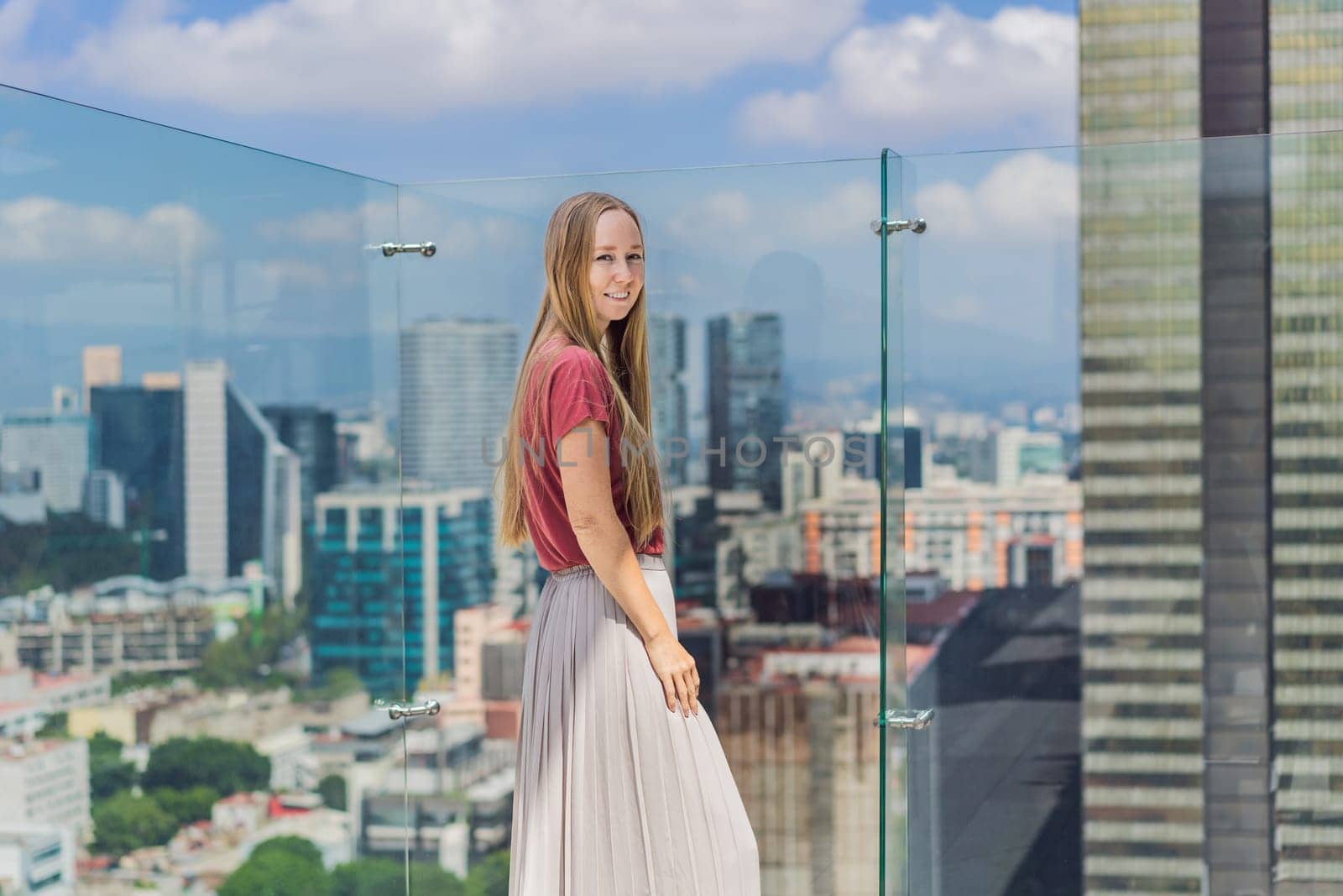 Female tourist or businesswoman standing on a skyscraper rooftop with a panoramic view of Mexico City. Travel or international business in Mexico concept.