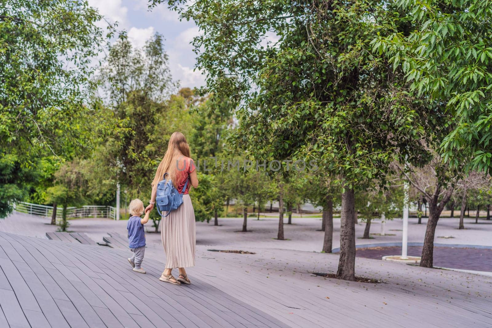 Mother with her toddler son walking in the park. Family bonding, outdoor exploration, and parenting concept.