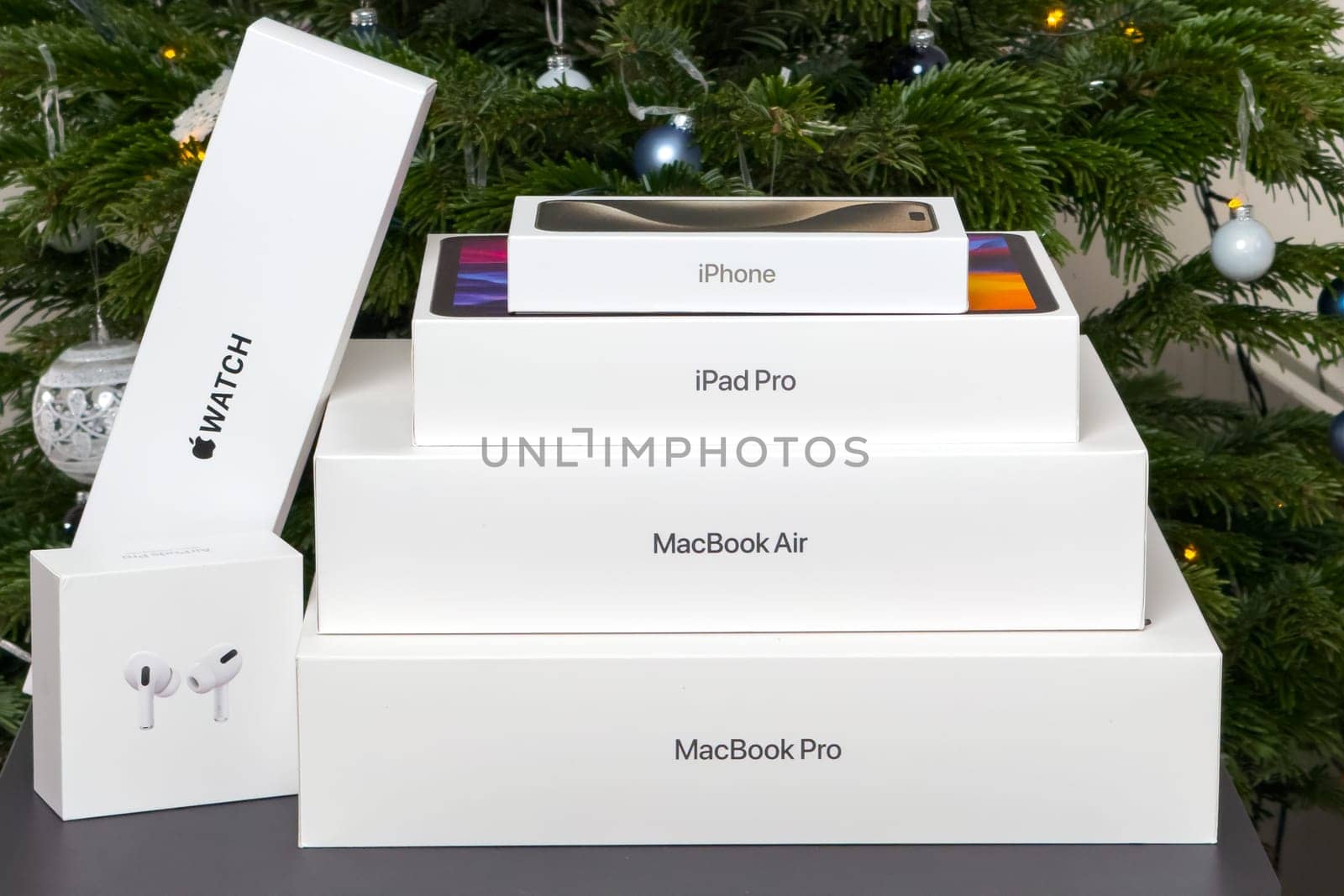 BERLIN , GERMANY - JANUARY 14 2024: Gift boxs with air pods, Apple watch, Macbook Pro, Macbook Air, iPad pro and iPhone under Christmas tree.