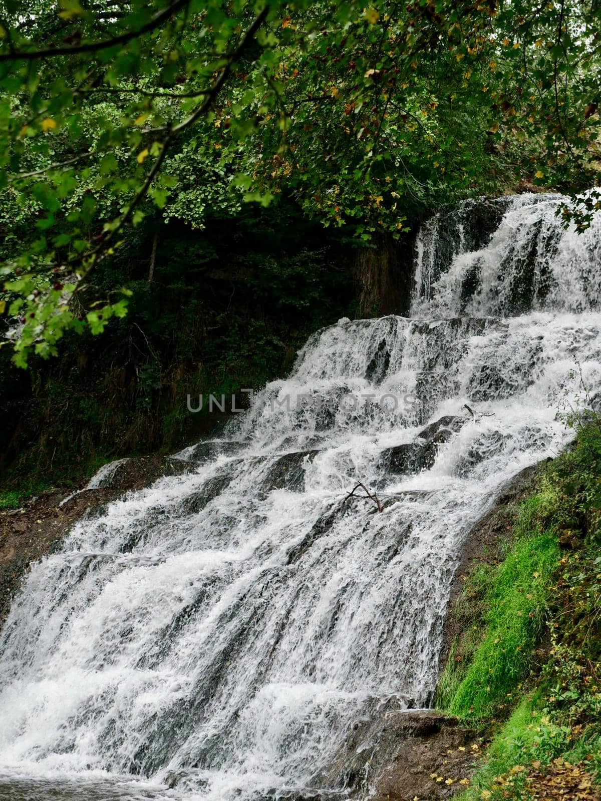 Chervonohorod Dzhuryn waterfall in summer in Ukraine. Travel nature Carpathian Mountains in cloudy cool weather, vertical