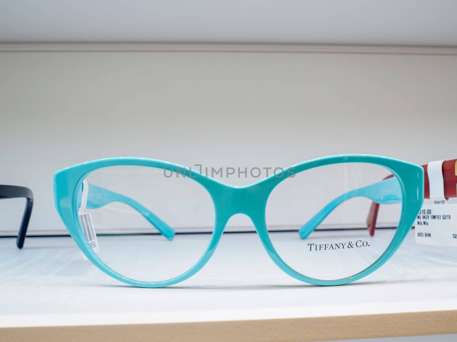 Pair of tiffany and co. Teal cat eye eyeglasses are sitting on a shelf in an optometrist shop, awaiting their owner
