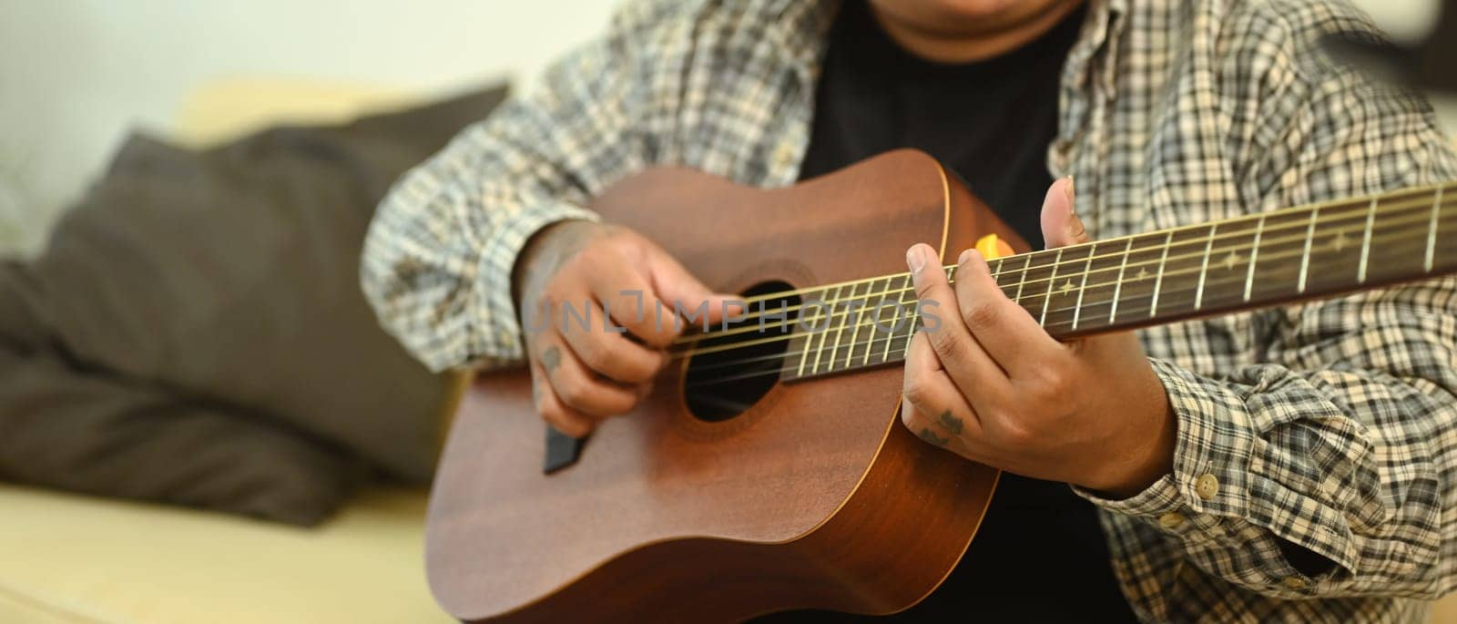 Close up shot of man playing an acoustic guitar. Relaxation, hobbies, and creativity concept.