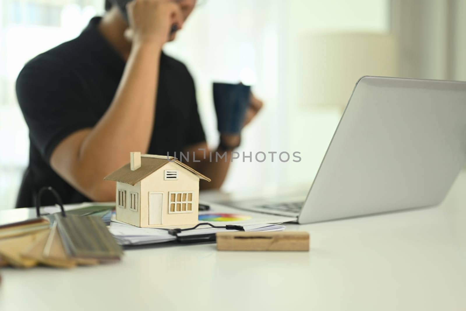 Small house model and color swatches on desk representing architectural design or real estate development.