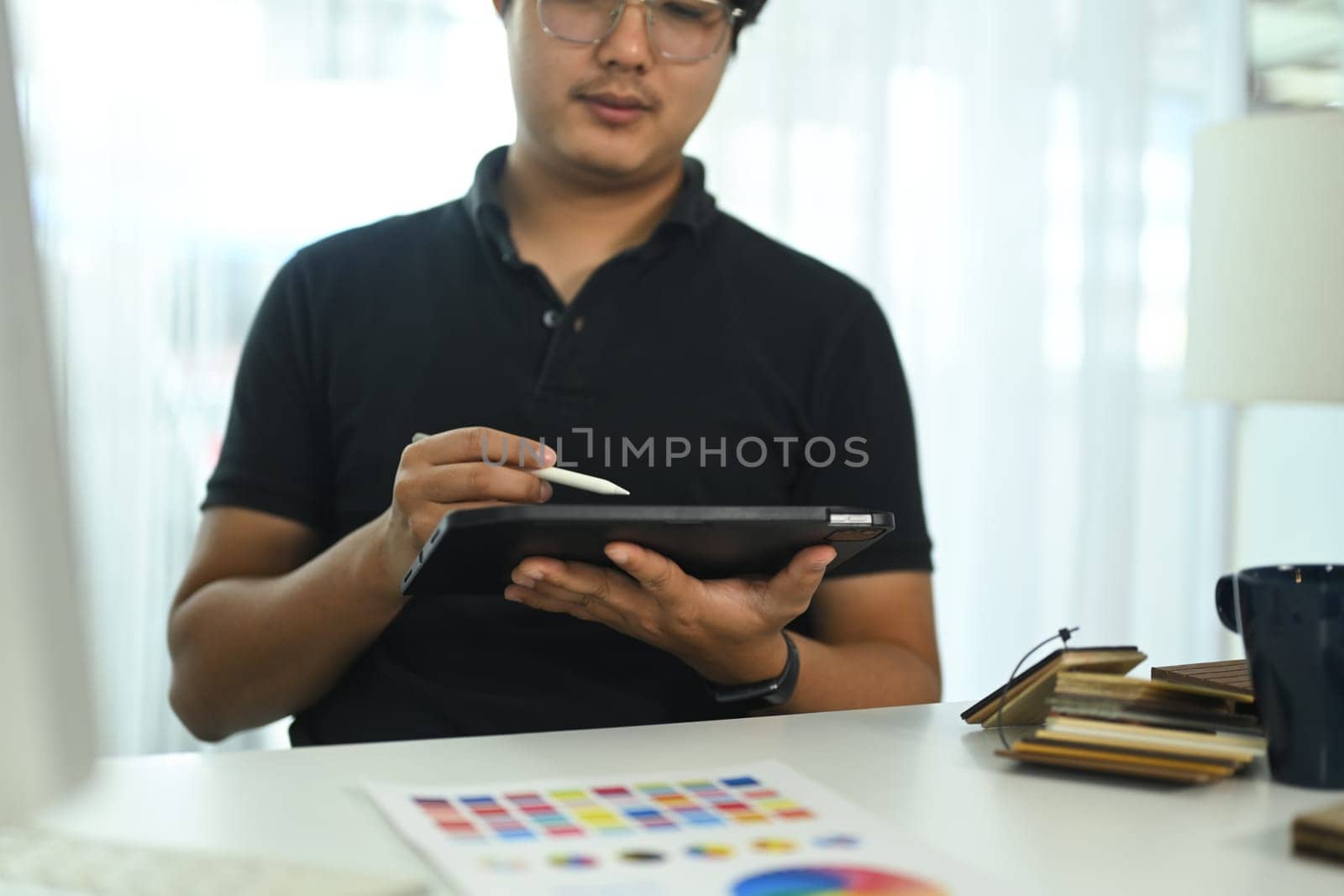 Interior designer working with a digital tablet and stylus, sketching or reviewing design project at office.