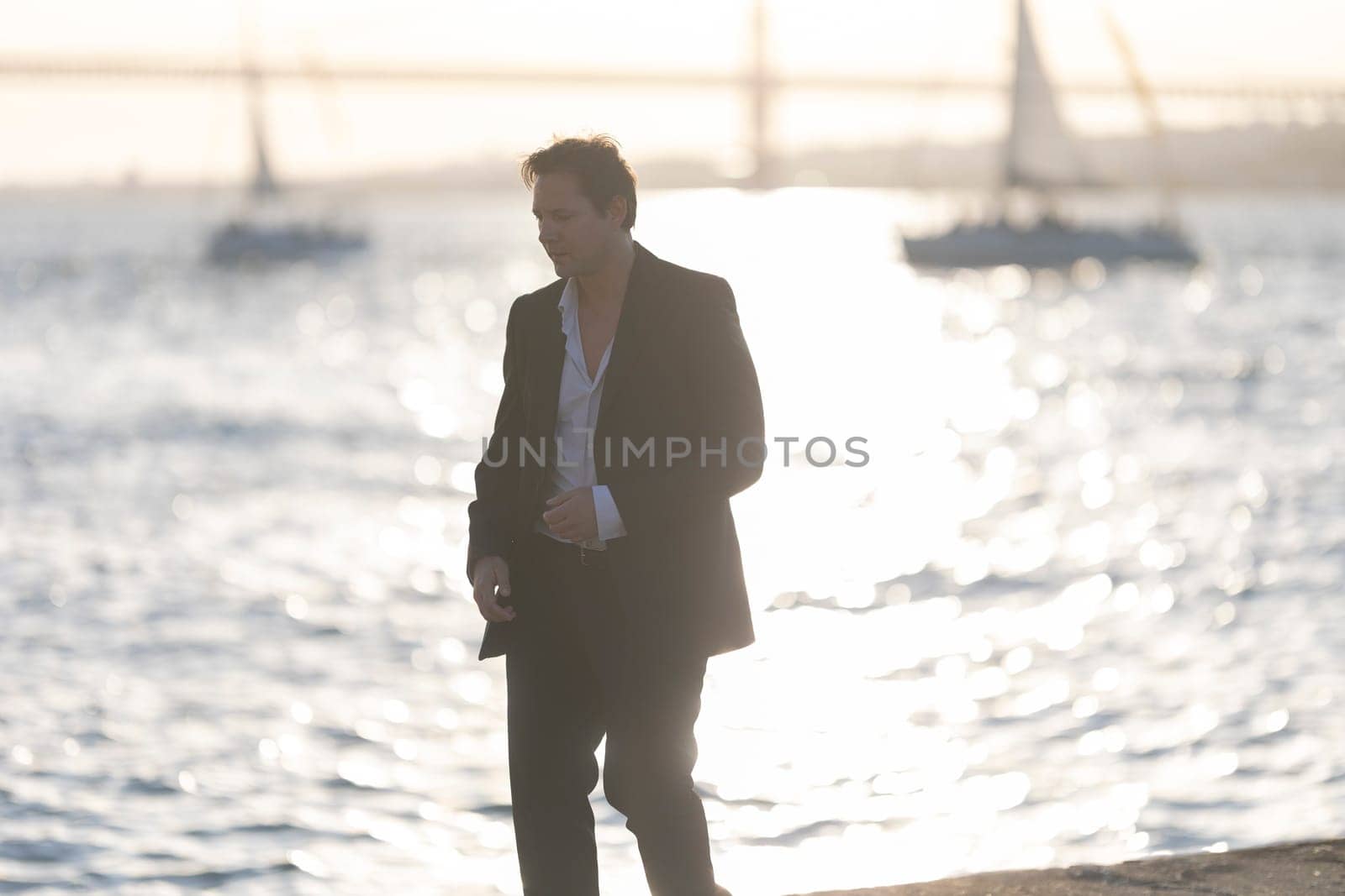 Businessman walking along the shore of san francisco bay at sunset
