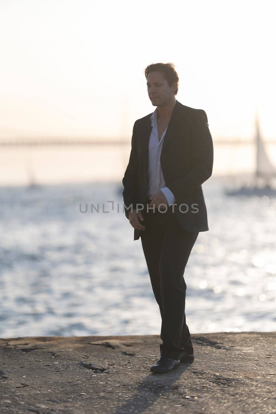 Businessman is walking on a pier at sunset, deep in thought