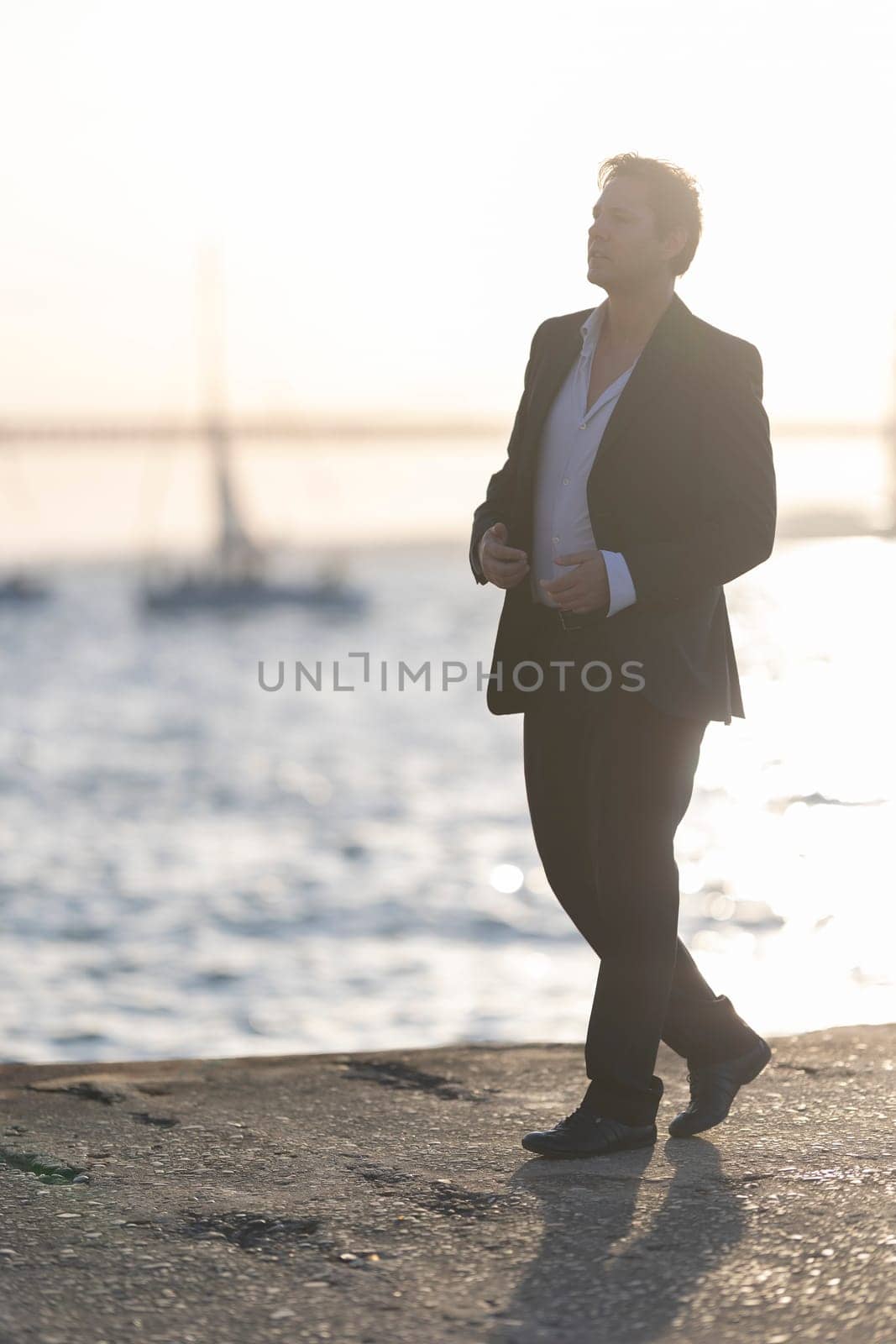 Businessman is walking on a pier at sunset, enjoying the view of the water and the boats