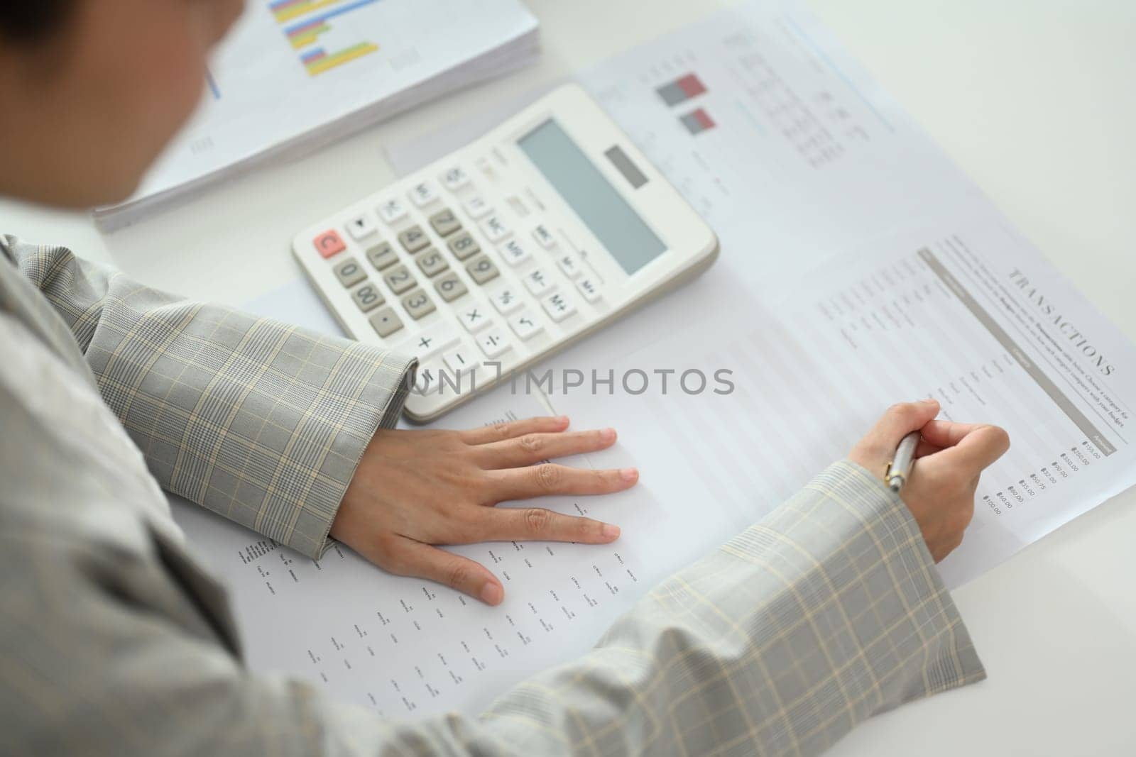 Close up businesswoman working on financial documents, budgeting or financial analysis at desk.