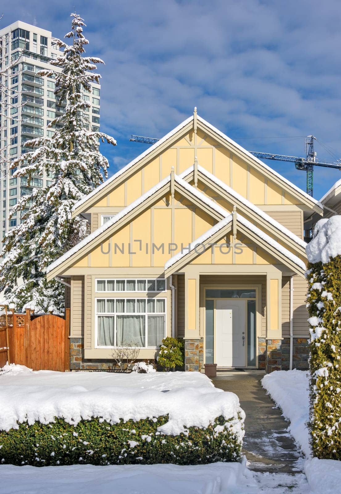A perfect neighbourhood. Modern high-rise and private residential house in snow on winter season in British Columbia, Canada.