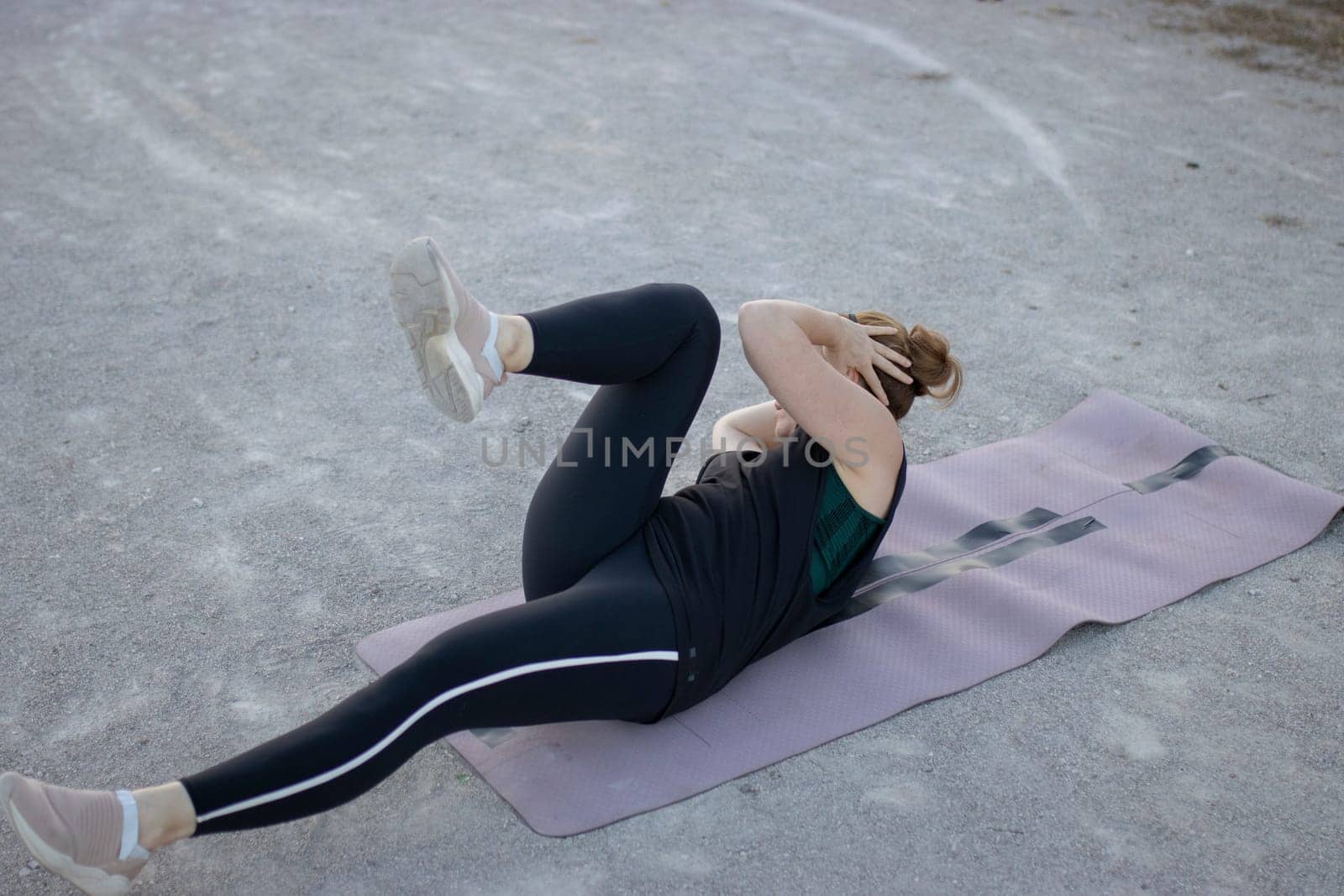 Young woman is improving her abdominal muscles by doing crunches on a mat