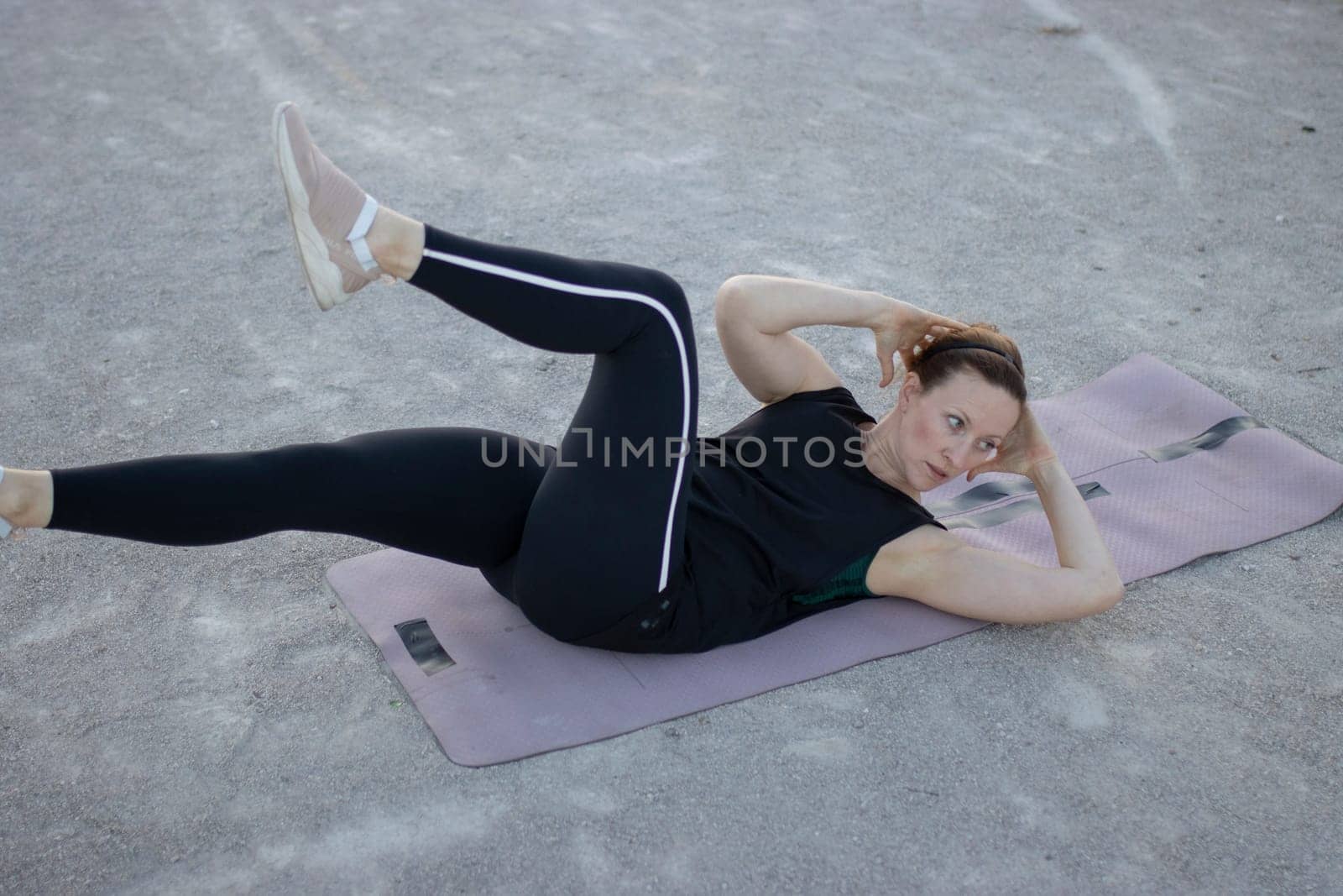 Sporty woman is strengthening her abdominal muscles while exercising outdoors