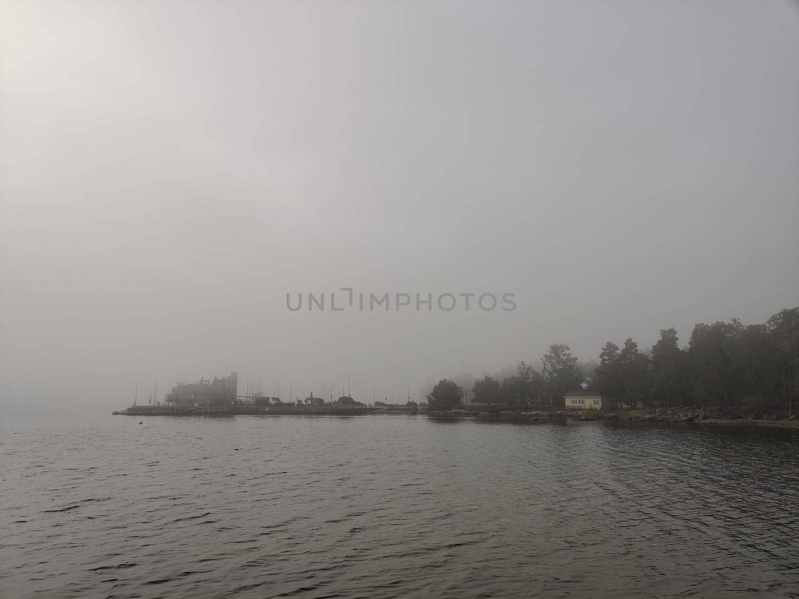 Relaxing foggy Northern autumn scene with swimming platform, pontoon or Wooden pier with a steel ladder into a Baltic sea. Autumn holiday vacation in Finland with beautiful sea