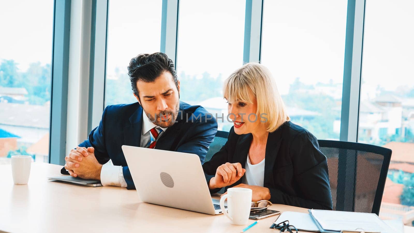 Two business people talk project strategy at office meeting room. Businessman discuss project planning with colleague at modern workplace while having conversation and advice on financial report. Jivy