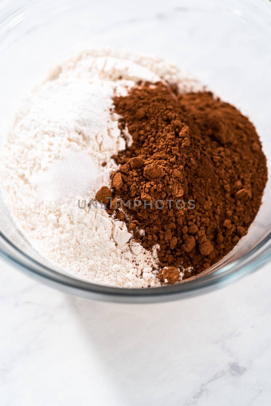 Mixing ingredients in a large glass mixing bowl to bake red velvet bundt cake with cream cheese glaze.