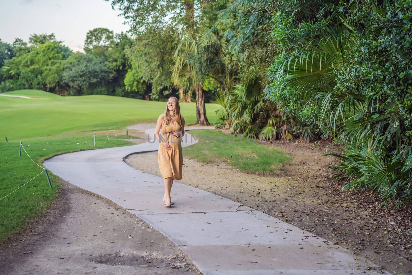 happy pregnant woman walking in the park.