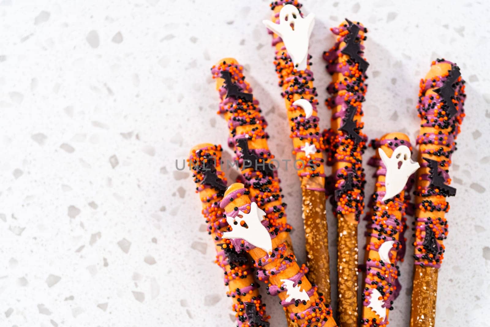 Flat lay. Halloween chocolate-covered pretzel rods with sprinkles on a kitchen counter.