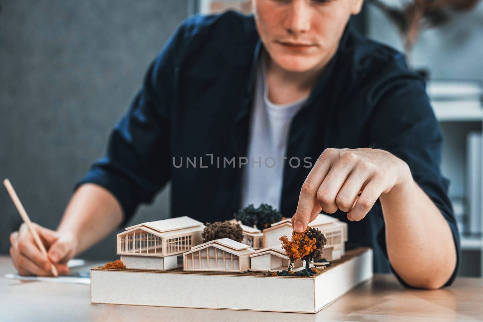 Architect designer studies elegant house model, reviewing structure design for improvement with construction plan on table. Creativity and innovation in architectural design. Iteration