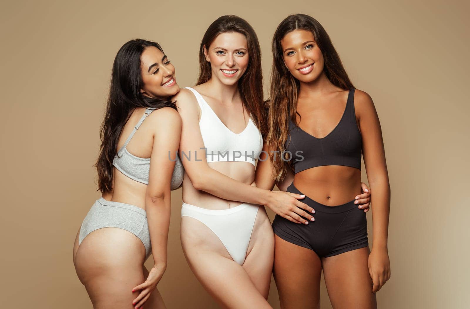 Glad millennial diverse women in underwear with different body types enjoy beauty care, isolated on beige background, studio. Anti cellulite, self love, spa treatments, wellness, modern lifestyle