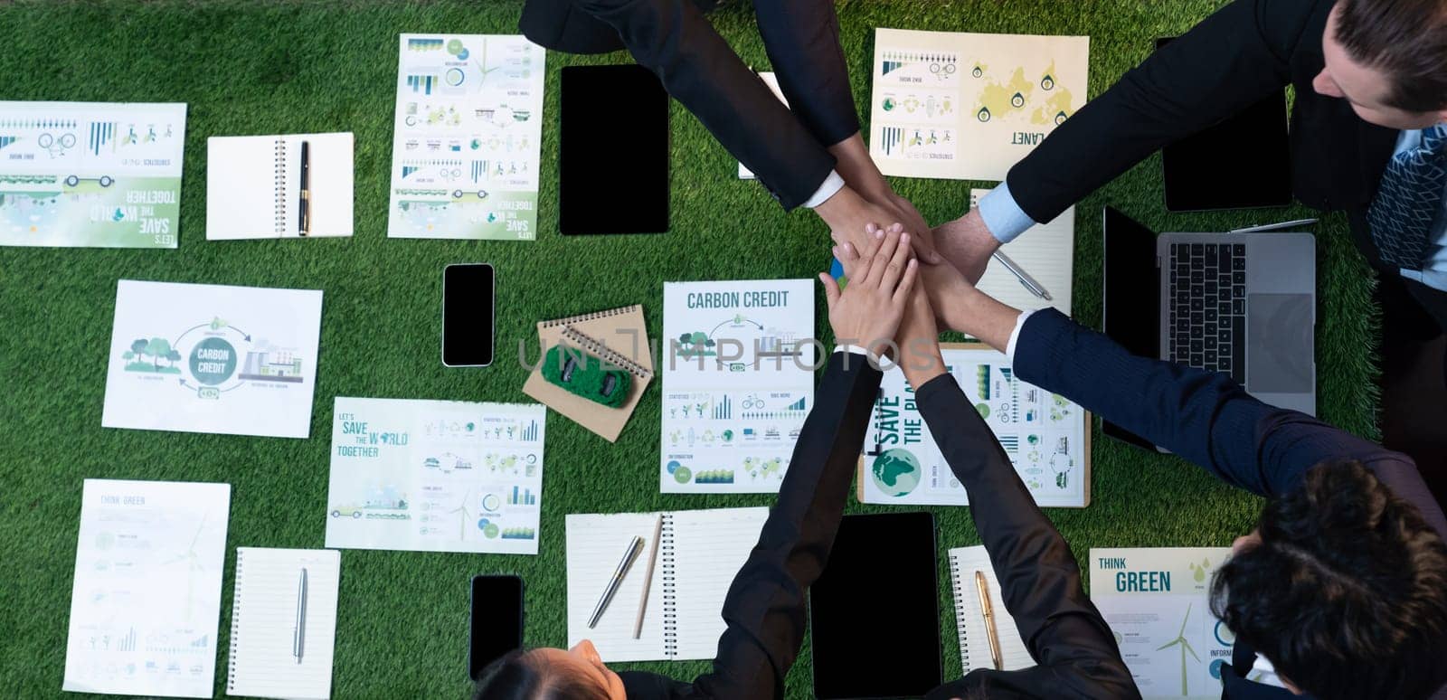 Business synergy in panoramic top view banner of business people holding hand together as team building for eco regulation for environmental protection to contribute sustainable future. Quaint